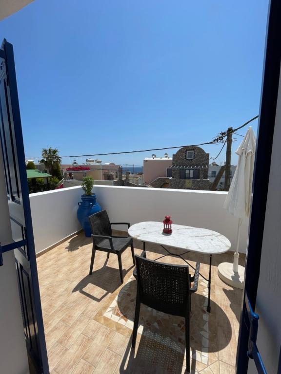 een balkon met een tafel en stoelen en uitzicht op de oceaan bij Leonidas Apartments in Kamari