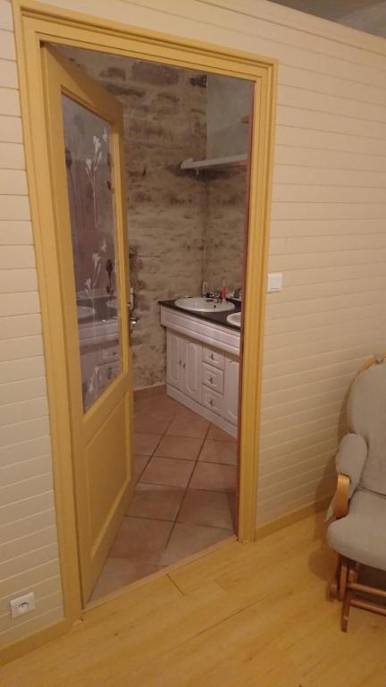 une porte menant à une salle de bains avec lavabo. dans l'établissement Chambre d'hôte au pays des abers, à Lannilis