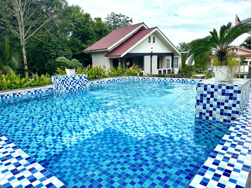 una piscina con azulejos azules y blancos frente a una casa en Kapal Terbang Guest House Langkawi, en Pantai Cenang