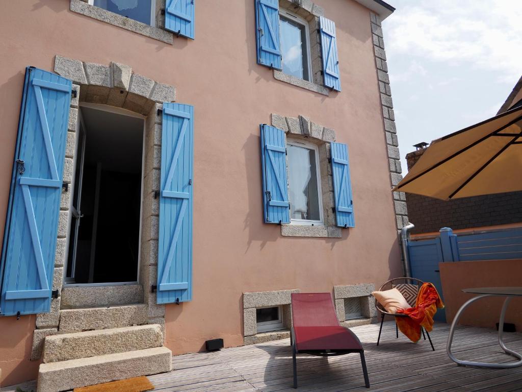 a building with blue windows and chairs on a patio at 30 m des Plages - Port du Magouër - 6 invités in Plouhinec