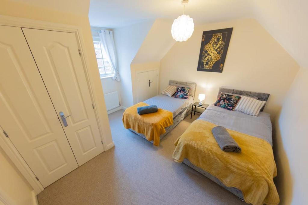 een slaapkamer met 2 bedden met gele lakens bij Manhattan Hideaway Warrington in Burtonwood