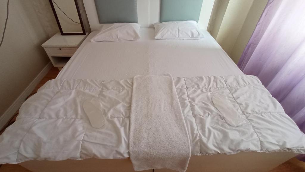 Una cama con sábanas blancas y toallas. en ESEN OTEL, en Antalya