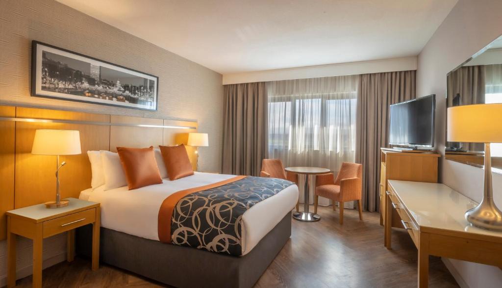 um quarto de hotel com uma cama, uma secretária e uma televisão em Clayton Hotel Liffey Valley em Clondalkin