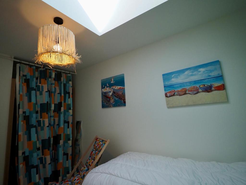 a bedroom with a bed and a chandelier at 30 m des Plages - Port du Magouër - 6 invités in Plouhinec