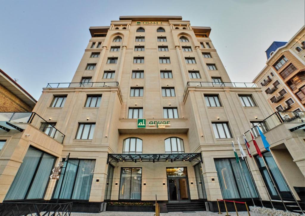 un edificio alto bronceado con un letrero. en Al Anvar Halal Hotel by HotelPro group, en Tashkent