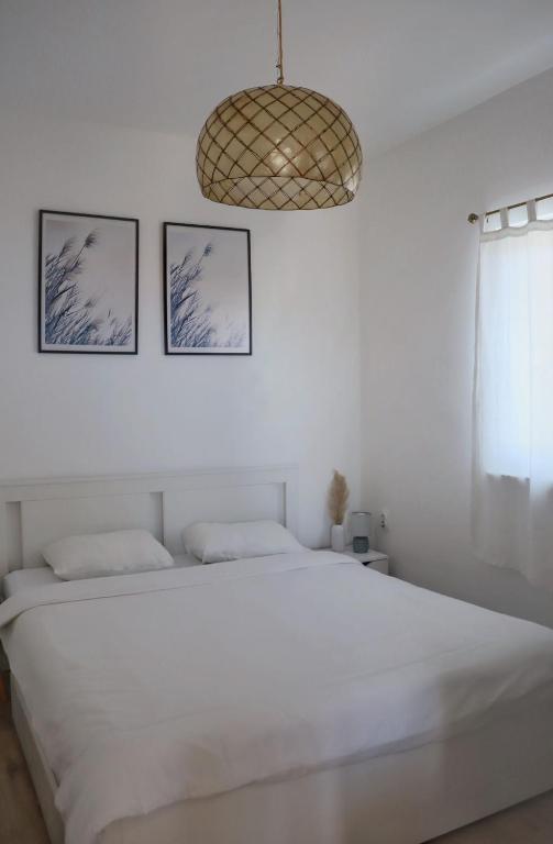 a white bedroom with a bed and two pictures on the wall at Apartment Elena in Sumartin