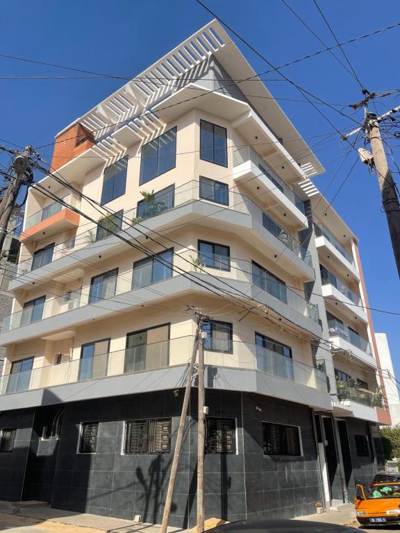 a tall white building with a car in front of it at Residence Martha in Dakar