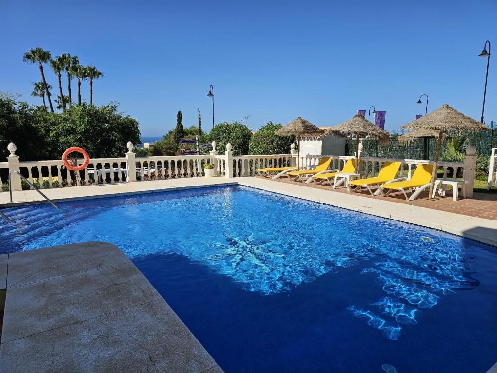 米哈斯科斯塔的住宿－Apartamento SEA VIEW Celeste Costa del sol Playa Chapparal，一个带椅子和围栏的大型蓝色游泳池
