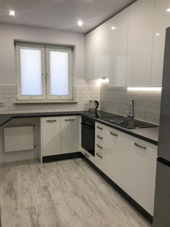 a kitchen with white cabinets and a sink at Ustka Apartament Na Wydmie in Ustka