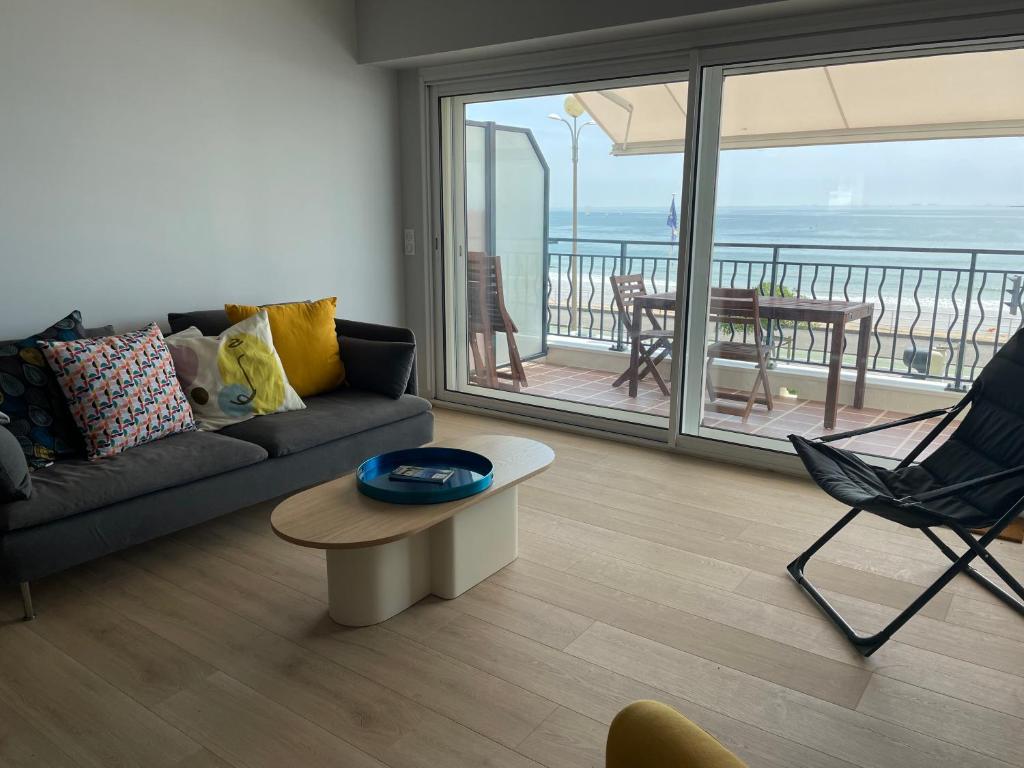 d'un salon avec un canapé et une table ainsi que d'un balcon. dans l'établissement Élégant logement avec vue sur l'océan, à La Baule