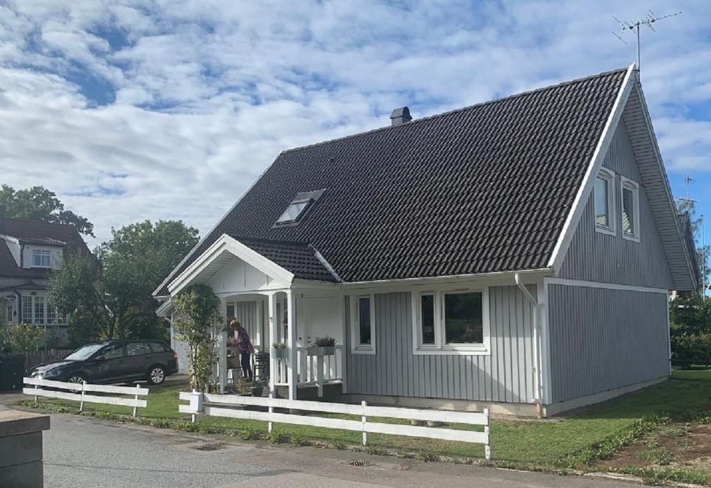 uma pequena casa cinzenta e branca com uma cerca branca em Standard swedish family house em Ronneby