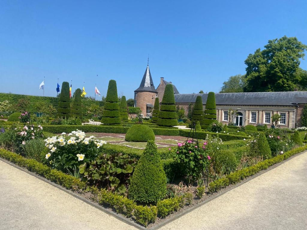 un jardín frente a un edificio con árboles y arbustos en The Lodge en Bilzen