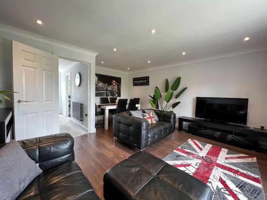 a living room with leather furniture and a television at Three Bed Townhouse with Parking in Telford