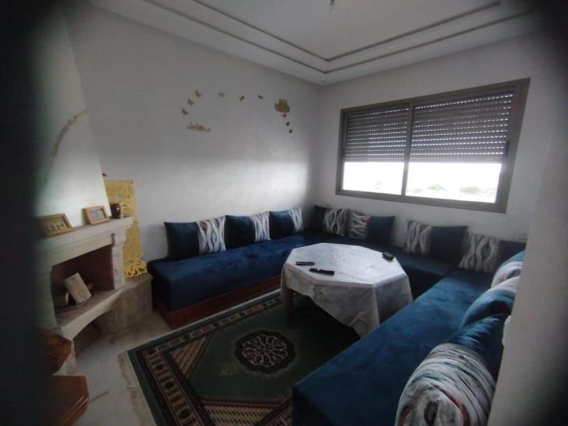 - un salon avec un canapé bleu et une table dans l'établissement Appartement a louer situé à proximité de la plage 500 m à dahoumy cité bouznika, à Bouznika