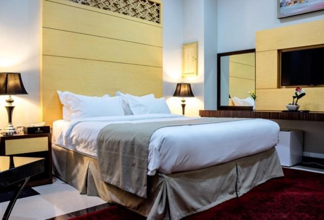 um quarto com uma cama grande e um espelho grande em Doha Dynasty Hotel em Doha