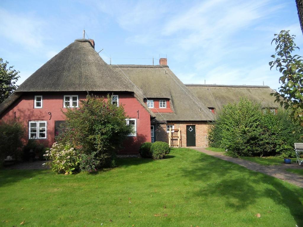uma grande casa de tijolos vermelhos com telhado de palha em Ole in Borgsum em Borgsum
