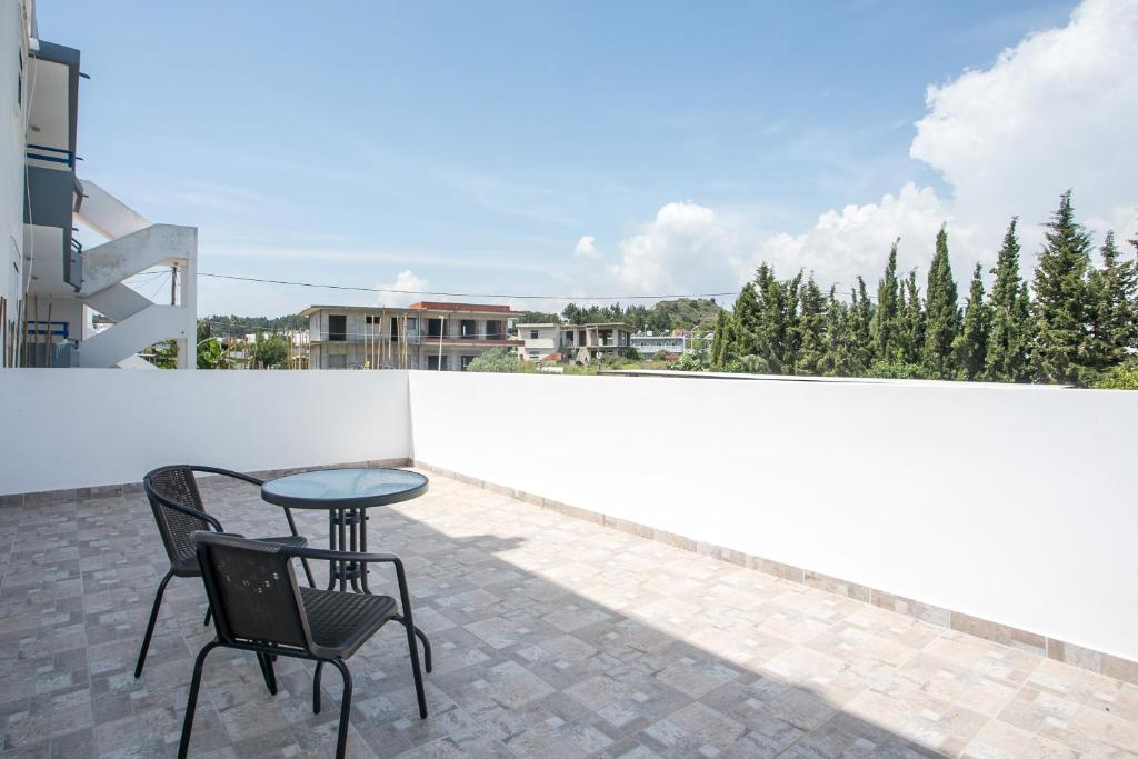 patio z 2 krzesłami i stołem na balkonie w obiekcie VOULA APARTMENTS w mieście Faliraki