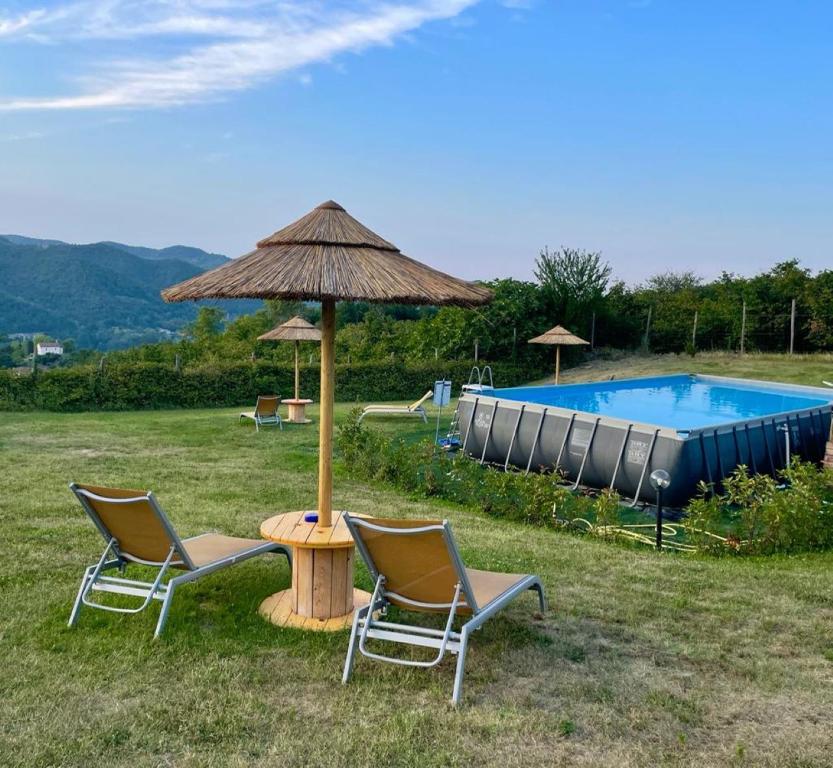 two chairs and a table with an umbrella and a swimming pool at Yurte in Langa in Bosia