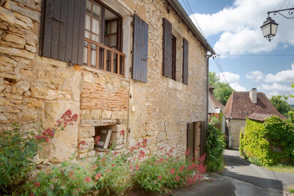 an old stone building with a window and flowers at La Petite Maison du Périgord in Tourtoirac
