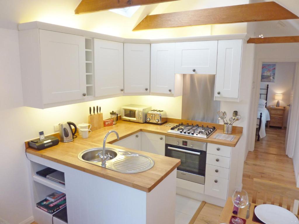 a kitchen with white cabinets and a sink at Luxury detached annexe in Kingsbridge with estuary walk to great pub & parking in Kingsbridge