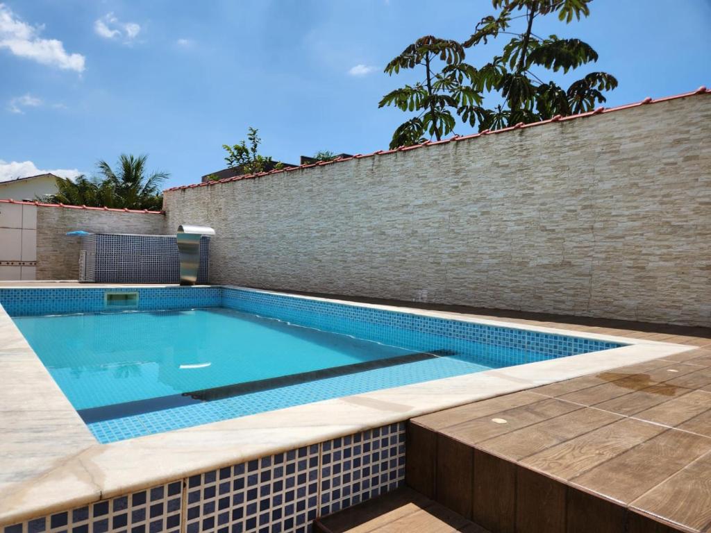 uma piscina em um muro de contenção de tijolos com uma parede de azulejos em Casa dos Andrade em Caraguatatuba em Caraguatatuba