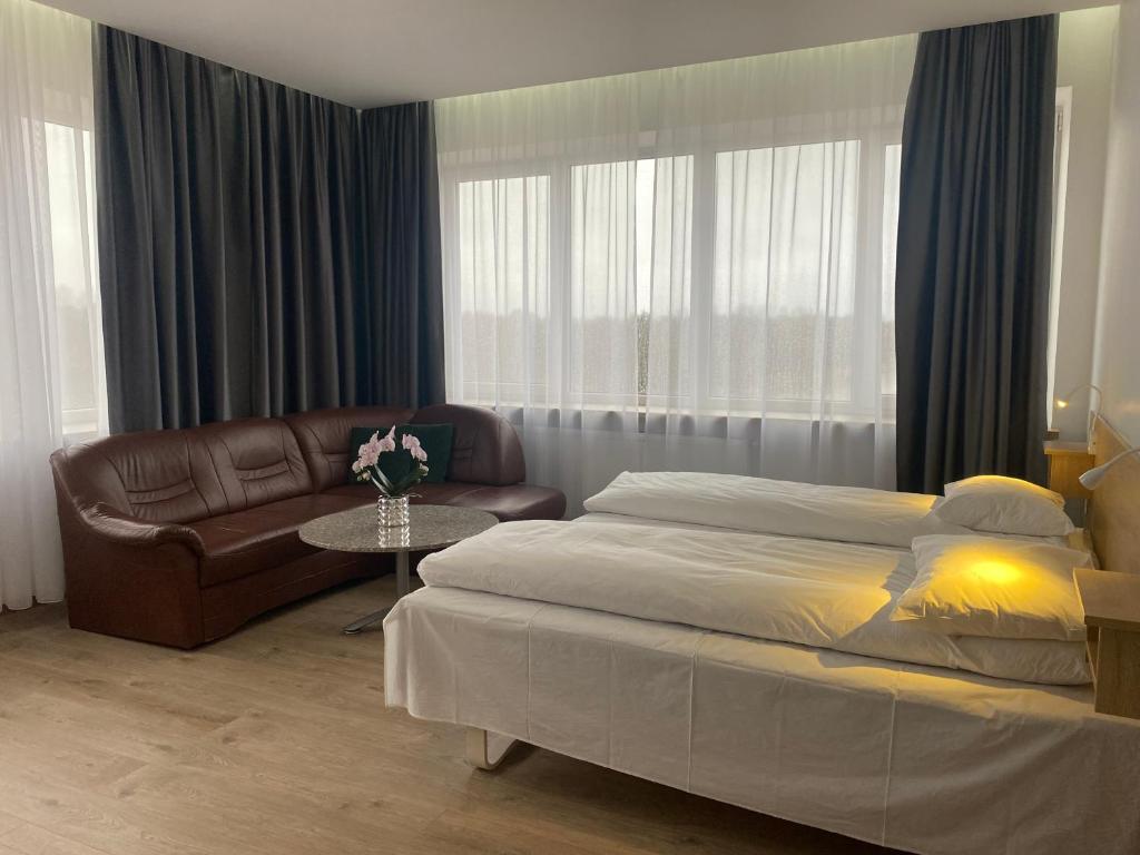 タウラゲにあるViešbutis Bangaのベッドルーム1室(ベッド1台、ソファ、テーブル付)
