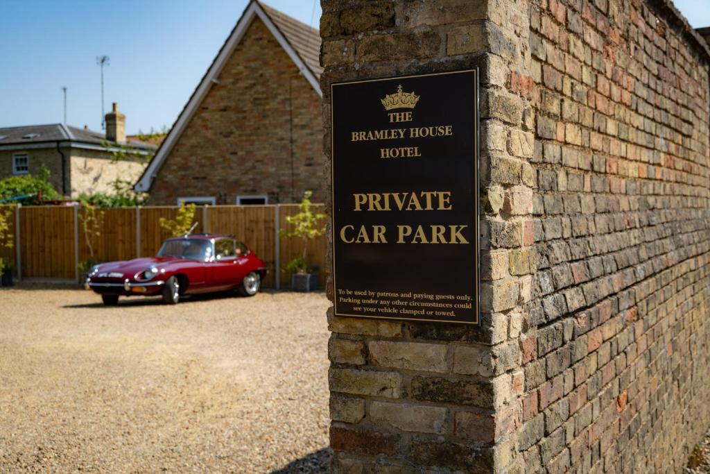 un panneau sur un mur de briques à côté d'un parking dans l'établissement The Bramley House Hotel, à Chatteris