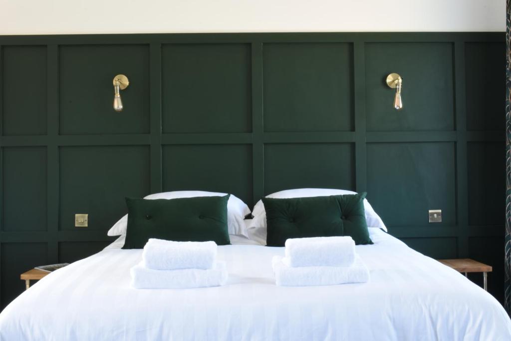 a bedroom with a large white bed with green walls at The Hop Merchant's House in Worcester