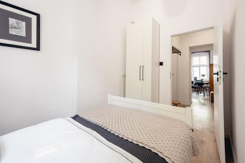 Apartamenty Woźna 14a, 2 rooms, self check in 24h في بوزنان: غرفة نوم بيضاء مع سرير وغرفة طعام