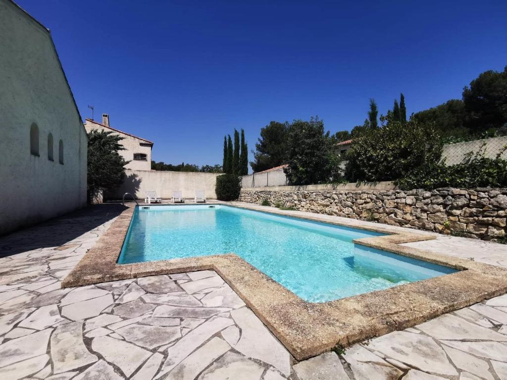 a swimming pool in a yard with a stone wall at L'Authentique - Villa Piscine Privative WIFI in Saint-Mitre-les-Remparts