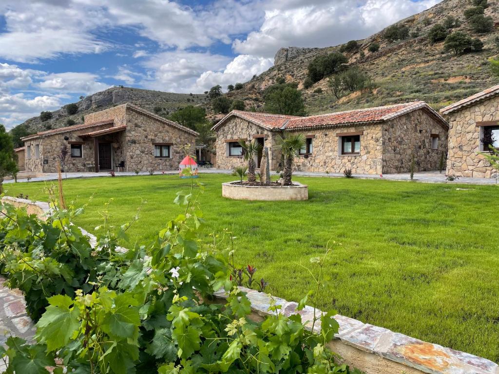 an exterior view of a stone house with a yard at Las Villas de Fuentidueña in Fuentidueña