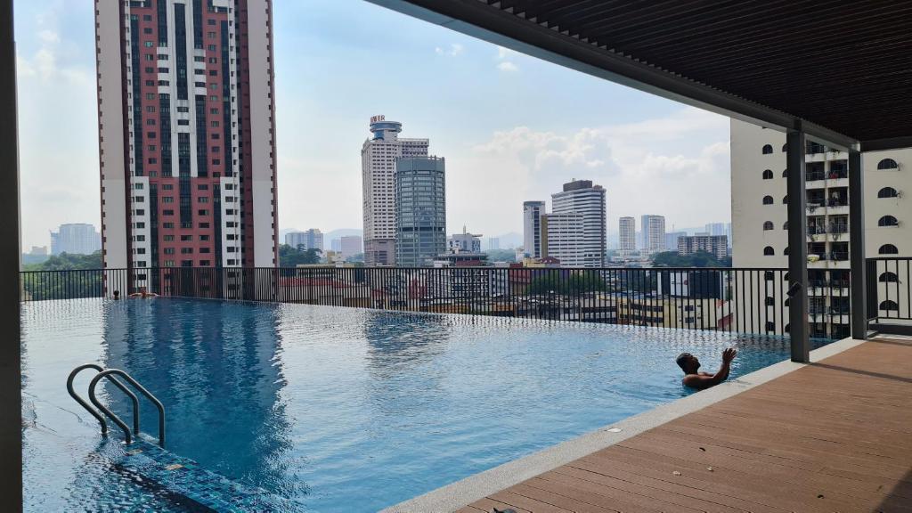 a person in a swimming pool on top of a building at Chambers Serviced Suites KLCC by Cozy Stay in Kuala Lumpur