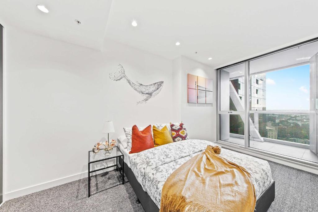 een slaapkamer met een bed en een groot raam bij A Cozy & Lux Apt Next to Southern Cross Station in Melbourne