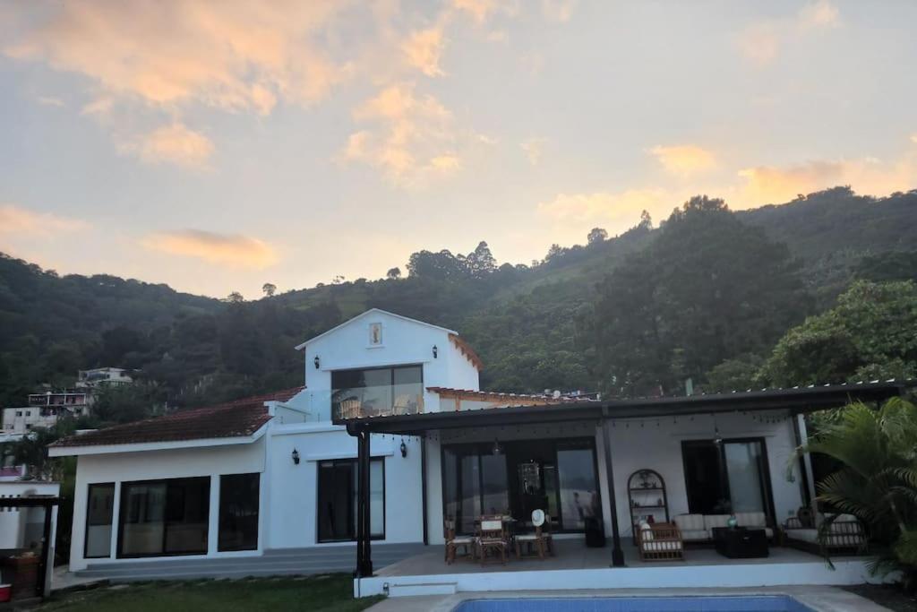 une maison blanche avec une montagne en arrière-plan dans l'établissement Chalet Santa Teresita, à Amatitlán