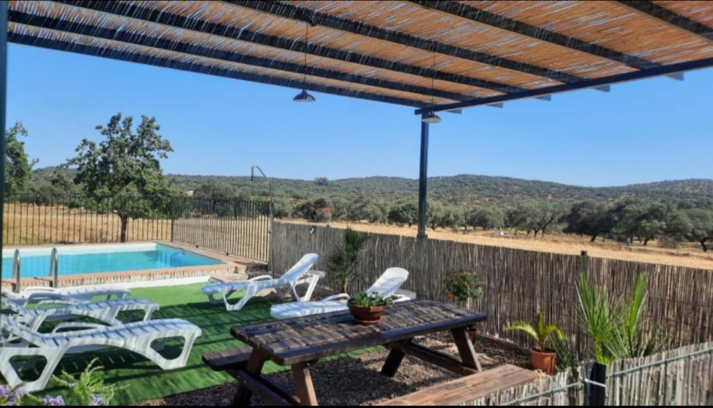 un patio con mesa, sillas y piscina en CASA RURAL LA DEHESILLA, en Cazalla de la Sierra