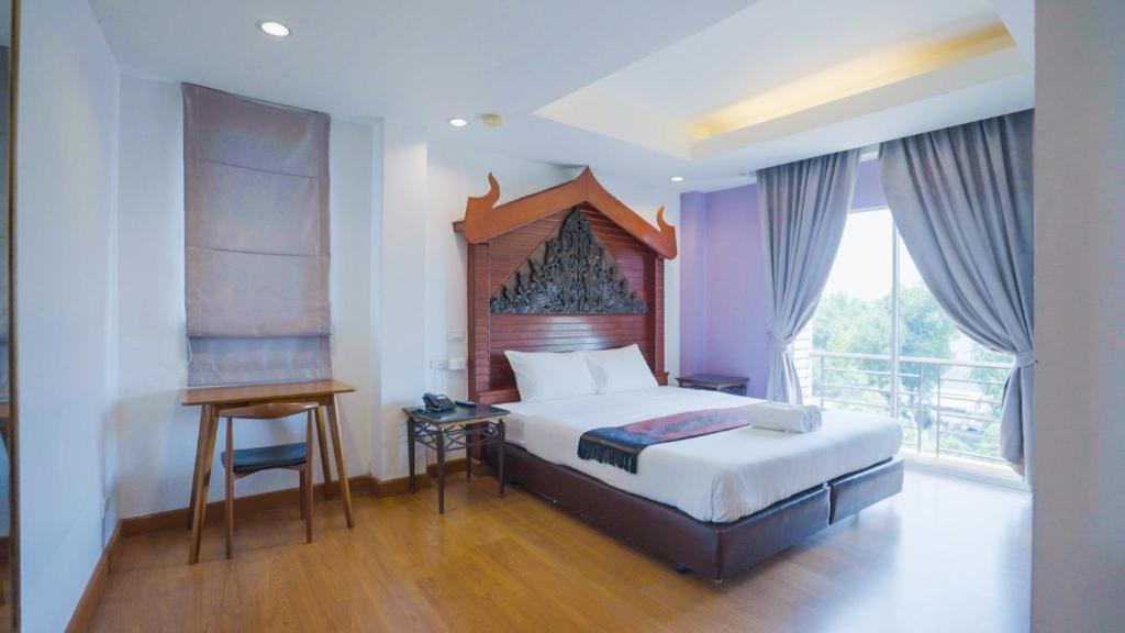 a bedroom with a bed and a desk and a window at Korbua House in Bangkok