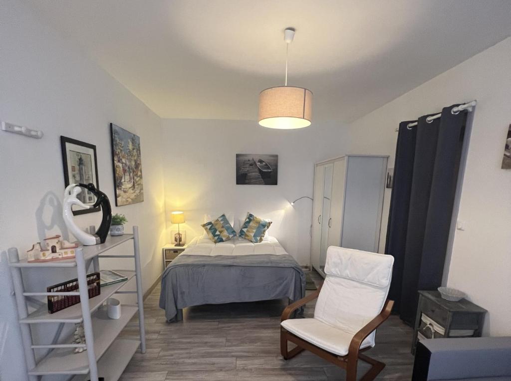 une chambre avec un lit et une chaise dedans dans l'établissement Le P'tit Gris, à Rochefort
