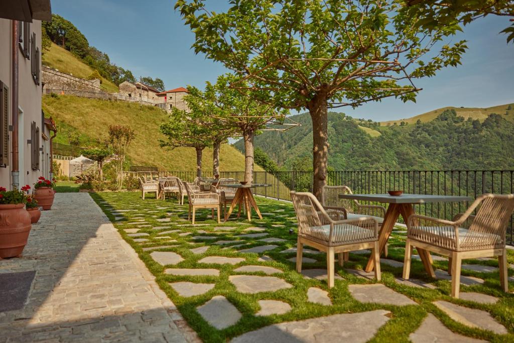 eine Terrasse mit Stühlen, einem Tisch und Bäumen in der Unterkunft "La Casa dei Gelsi" - Panorama Lodge by Stay Generous in Scudellate