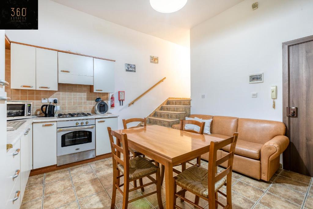 een keuken met een tafel en stoelen en een bank bij Lovely, comfy 2BR home with comfy sofa w/WIFI & AC by 360 Estates in St Paul's Bay