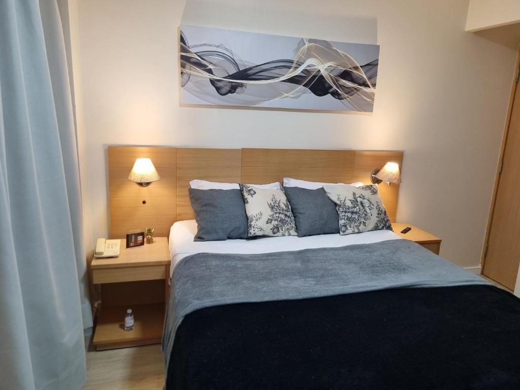 ein Schlafzimmer mit einem Bett und einem Schreibtisch mit zwei Lampen in der Unterkunft Apartamento Vista Maravilhosa - Próximo da Paulista in São Paulo