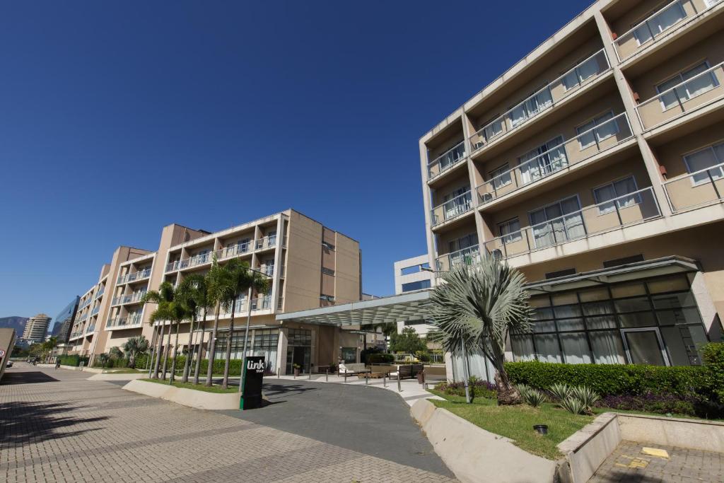 a building with palm trees in front of it at Promenade Link Stay Barra da Tijuca in Rio de Janeiro