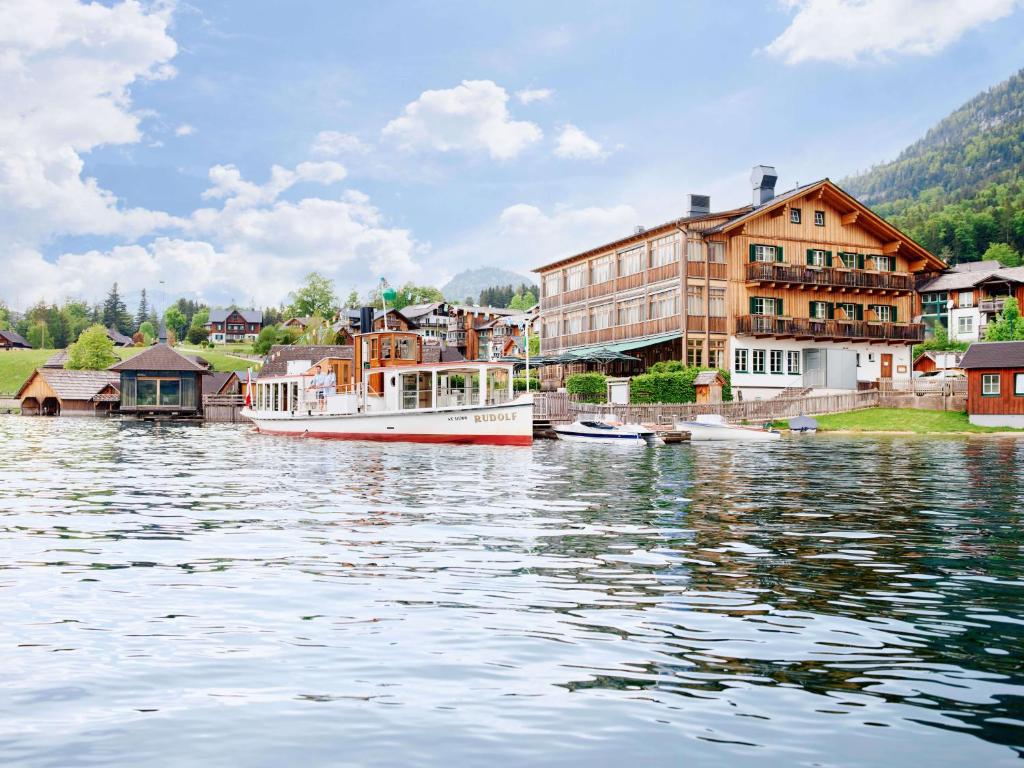 een boot is aangemeerd in een lichaam van water bij Seehotel Grundlsee in Grundlsee