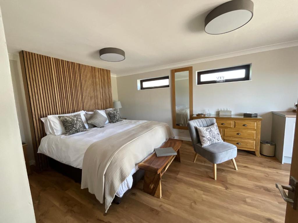 um quarto com uma cama grande e uma cadeira em The Garden Room at Amelia Cottage em Whiting Bay