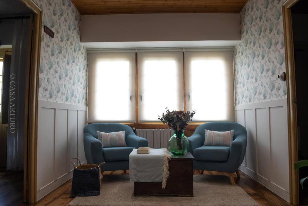 sala de estar con 2 sillas azules y mesa en Casa Arturo, en Triacastela