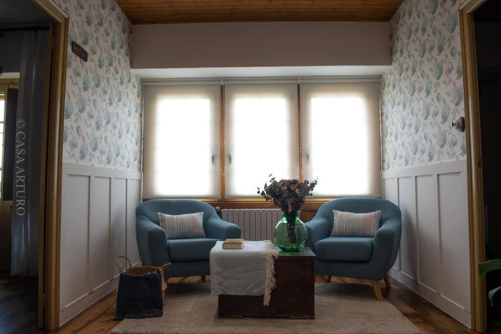 a living room with two blue chairs and a table at Casa Arturo in Treacastela