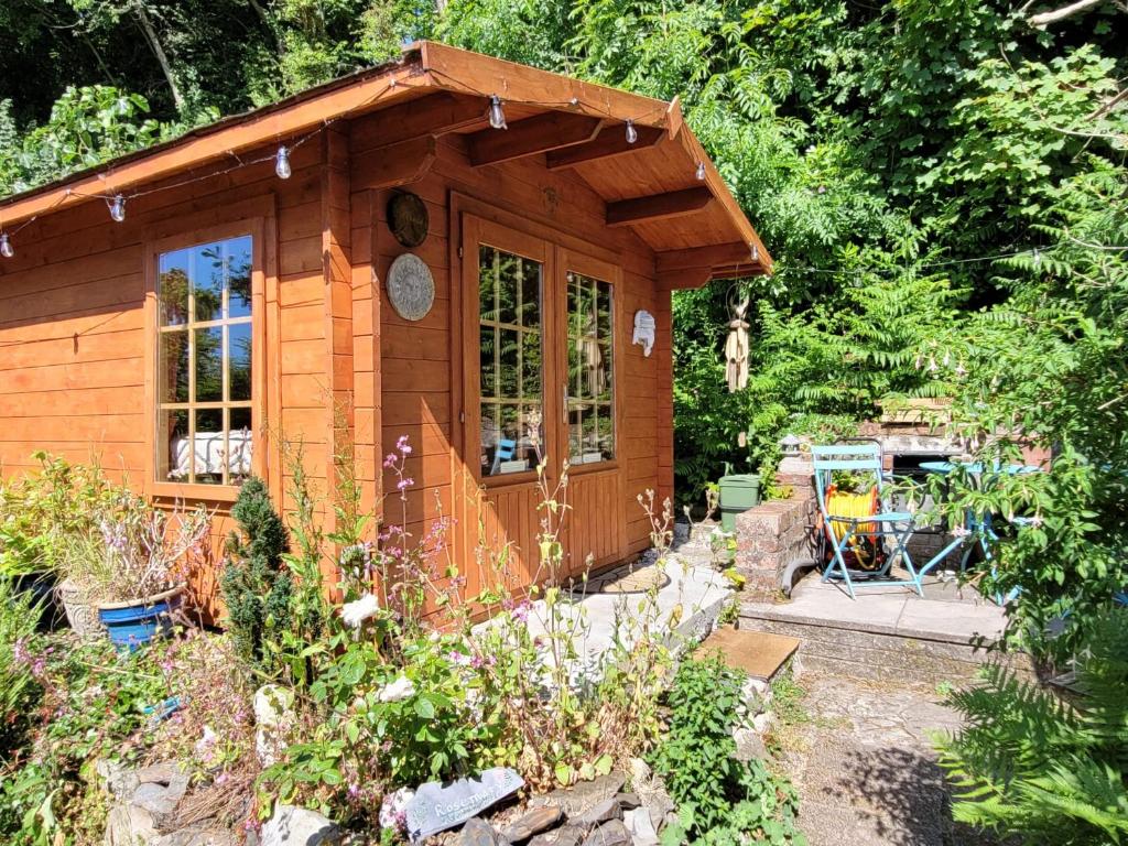 a small wooden cabin in a garden at Tan y coed's Rosemary Cabin in Conwy