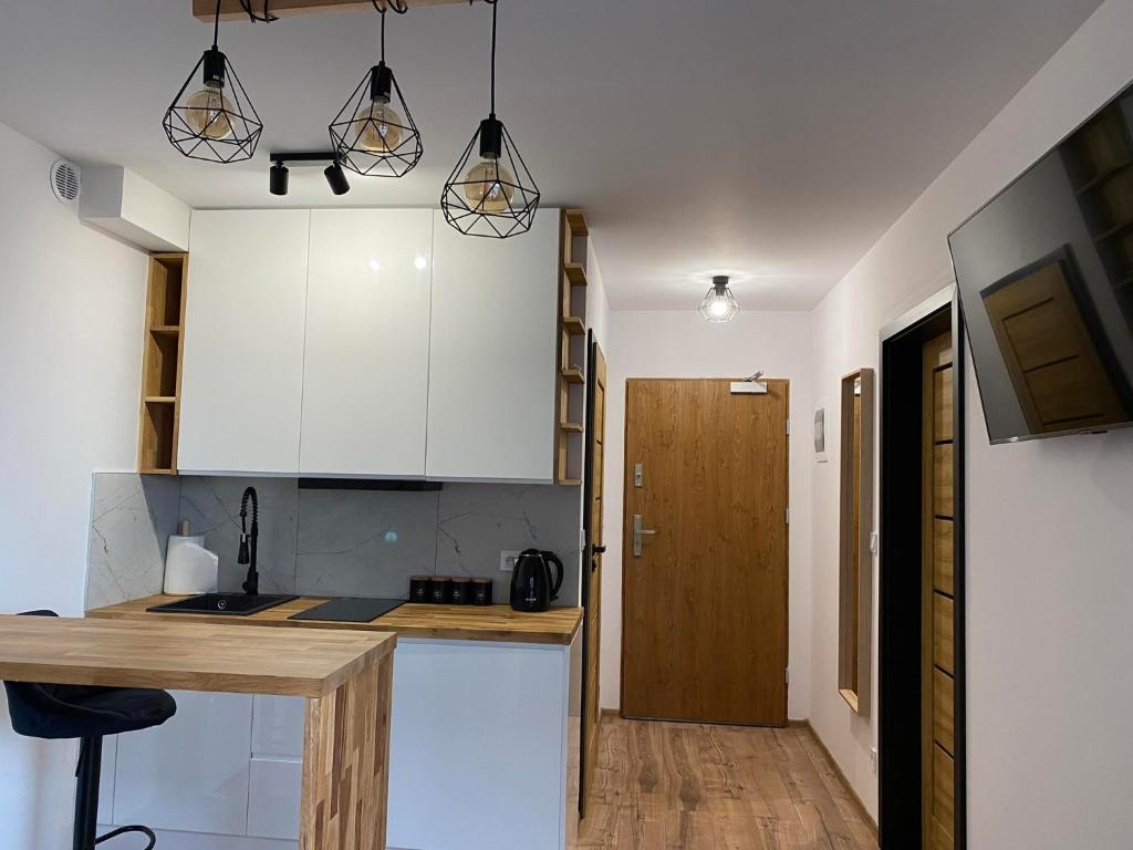une cuisine avec des placards blancs et un comptoir en bois dans l'établissement Apartament Spokojna Przystań, à Rowy