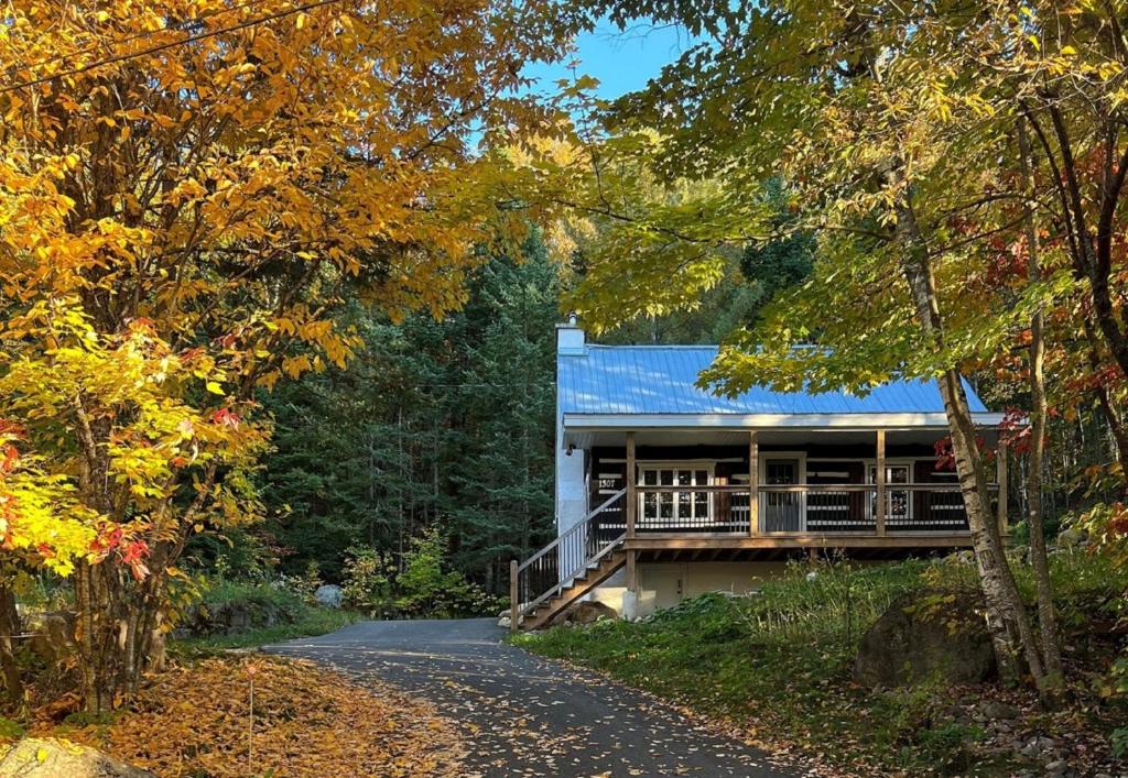 uma casa numa estrada na floresta em Chalet du Sous-Bois By My Tremblant Location em Saint-Faustin