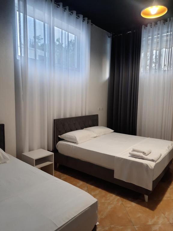 een slaapkamer met 2 bedden en ramen met witte gordijnen bij VILA PUSHIMI REGIS in Velipojë