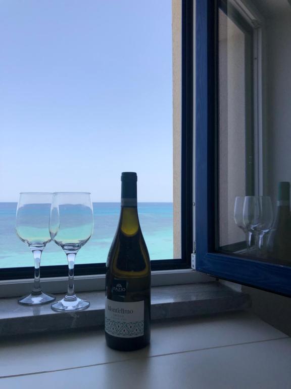 a bottle of wine and two wine glasses on a window at Le Mura in Trapani